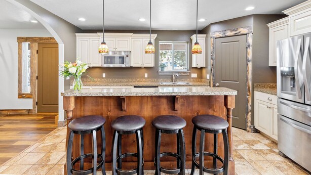 A kitchen with a central island, bar stools, a microwave, a sink, and pendant lighting. - Large house with lots of space. Just minutes away from national forest. (Thayne)