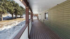 A covered wooden deck with a metal roof, a view of a snow-covered ground, and a building with siding. - Large house with lots of space. Just minutes away from national forest. (Thayne)