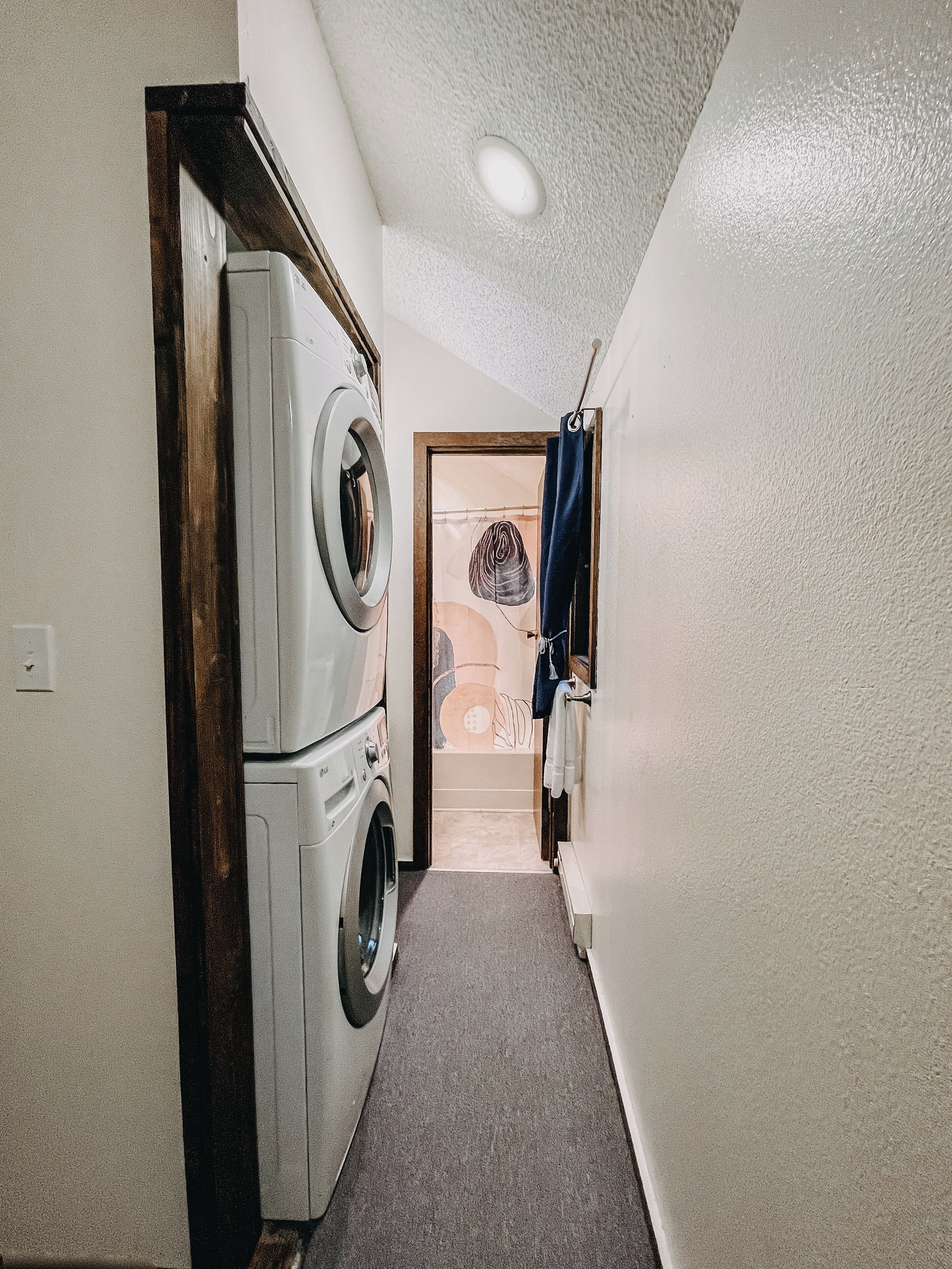 A laundry room with a washing machine and dryer, a towel rack, and a door leading to another room.