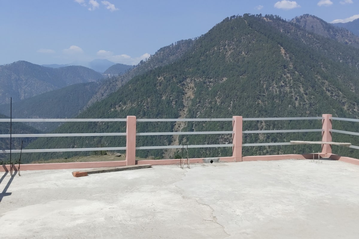 A concrete terrace with a metal railing overlooking a mountainous landscape.
