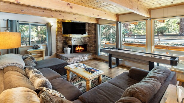 A cozy living room with a stone fireplace, large windows, and a comfortable seating area. - Summit's Trident, Spa, Game Room, Snow Summit (Big Bear Lake)