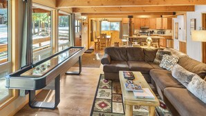 A cozy living room with a leather sofa, a coffee table with books, and a pool table. - Summit's Trident, Spa, Game Room, Snow Summit (Big Bear Lake)