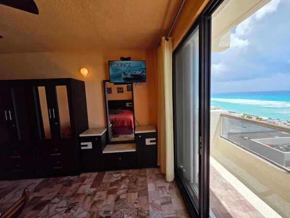 A room with a bed, a TV, and a view of the ocean.