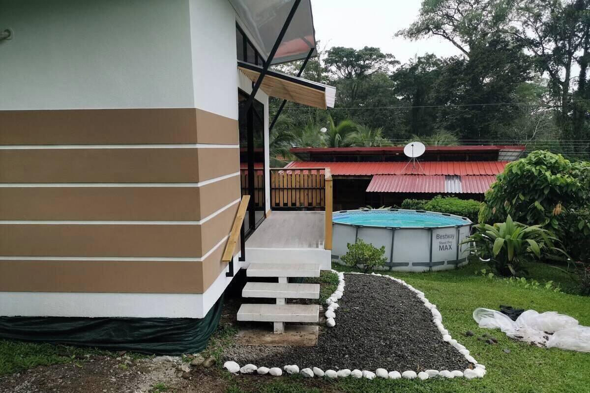 Ein Haus mit Veranda, Schwimmbad und Garten mit Kiesweg.