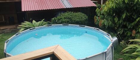 A swimming pool with a wooden deck and a satellite dish.