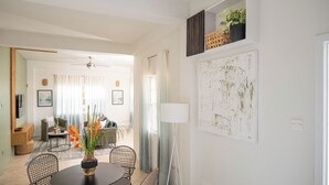 Una sala de estar moderna con comedor, ventilador de techo y un gran cuadro abstracto en la pared.