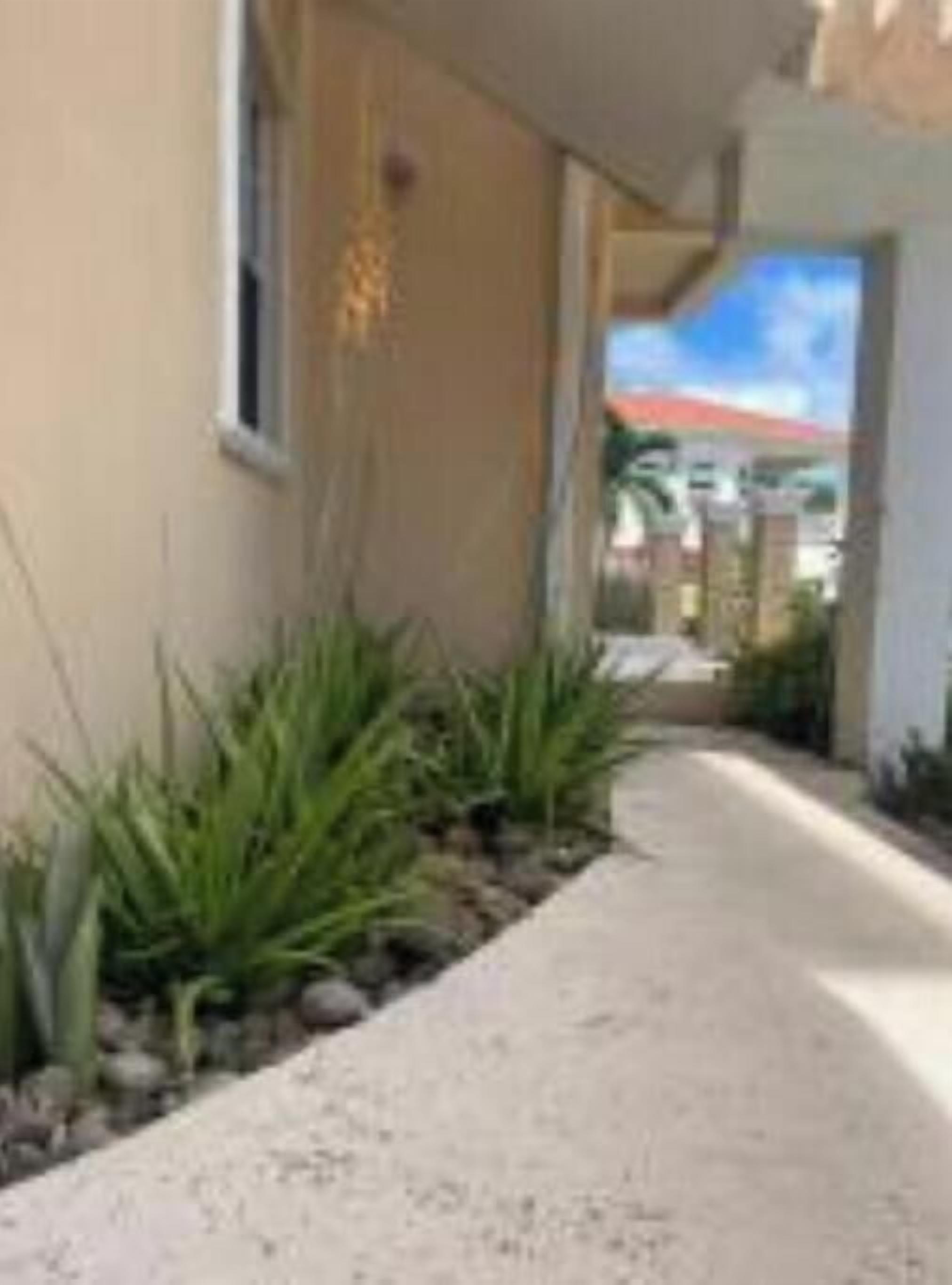 A pathway leading to a building with a beige exterior and a window.