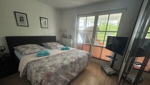 Een slaapkamer met een groot bed, een televisie en een raam met uitzicht.