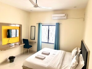 Une chambre d’hôtel équipée d’un lit, d’un bureau, d’une chaise, d’une télévision et d’un appareil de climatisation.
