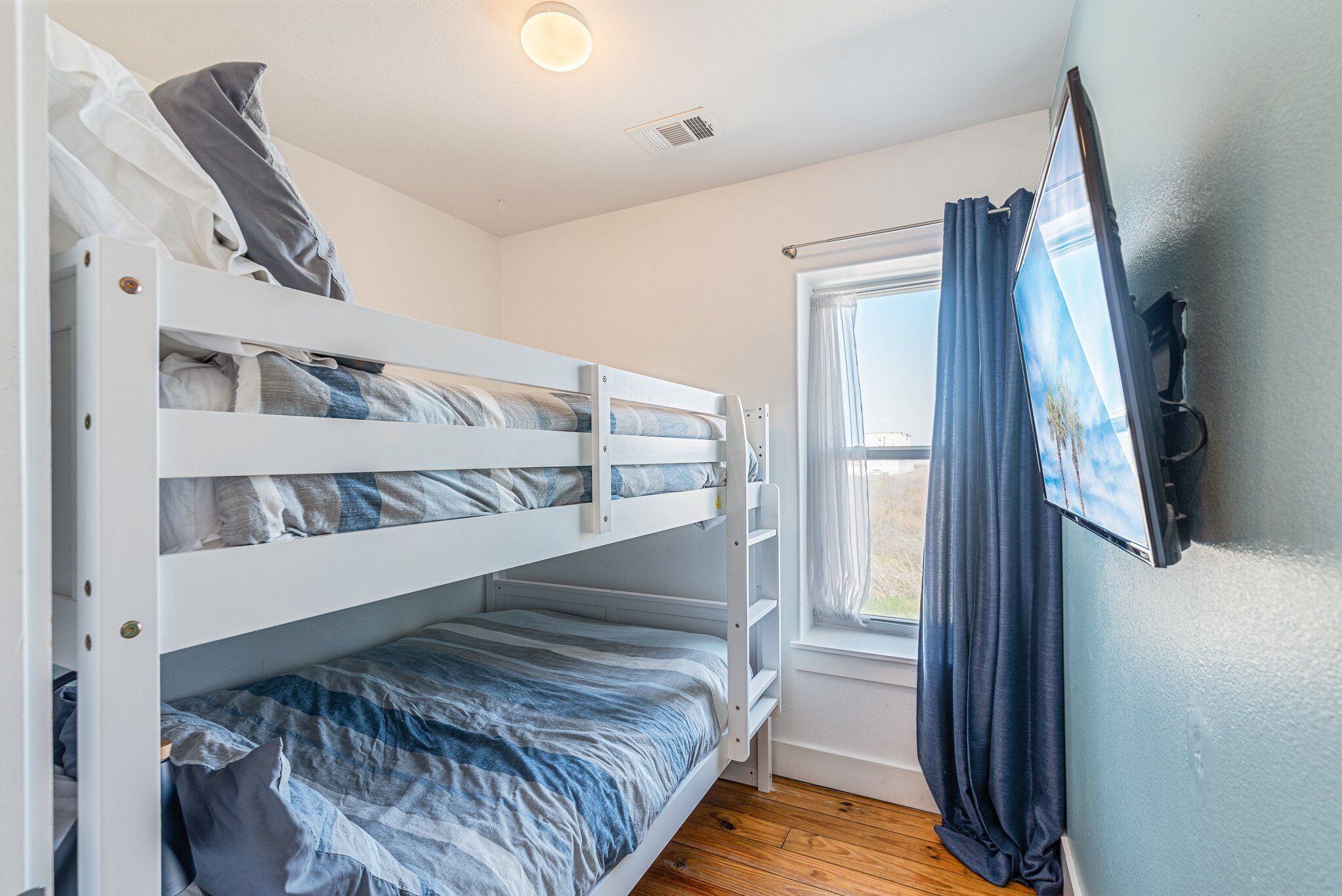A bunk bed room with a window and curtains.