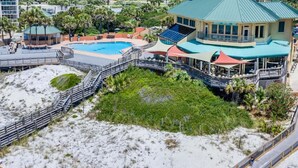 Un resort con una piscina grande, zona de playa y un edificio con techo verde.