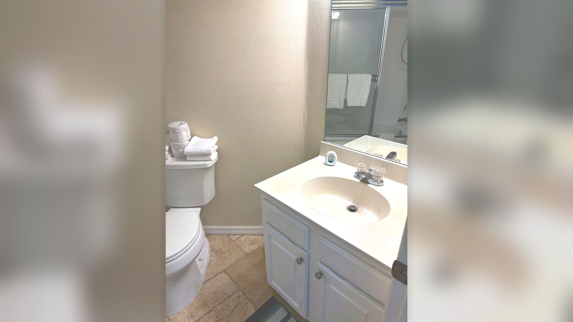 A bathroom with a toilet, a sink, and a mirror.