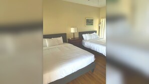 A hotel room with two beds, a nightstand with a lamp, and a painting on the wall.