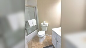 A bathroom with a glass-enclosed shower, a toilet, and a vanity with cabinets.