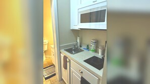 A compact kitchen with a microwave, sink, and a small countertop area.