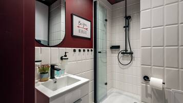 A modern bathroom with a white sink, glass shower enclosure, and a motivational quote on the wall.