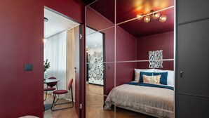 A modern bedroom with a bed, a desk, and chairs. - Crystal - by Kairos Apartments (Gliwice)