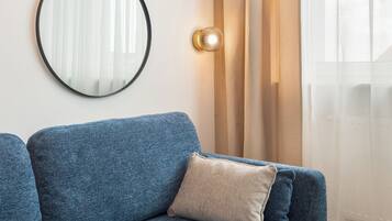 Ein blaues Sofa, ein runder Spiegel und eine Lampe an der Wand.