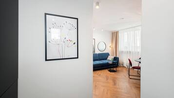 Una sala de estar moderna con un sofá azul, un espejo redondo y un comedor con mesa y sillas.