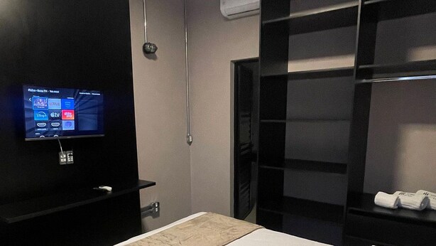 A hotel room with a bed, a TV on a stand, a wardrobe, and an air conditioning unit. - ADD HOTÉIS Congonhas (Sao Paulo)
