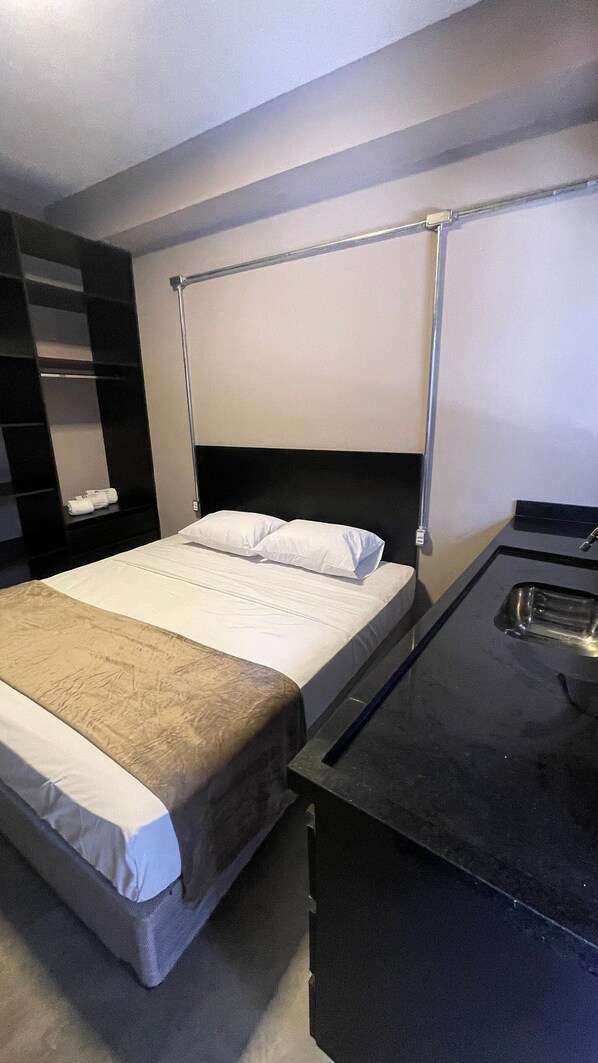 A modern hotel room with a single bed, a bedside table, a small desk, and a built-in shelf. - ADD HOTÉIS Congonhas (Sao Paulo)