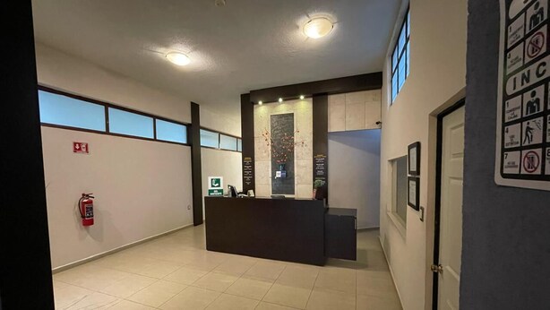 A reception area with a reception desk, a fire extinguisher, and a wall-mounted sign with emergency instructions. - Hotel Santa Julia  (Tecamachalco)
