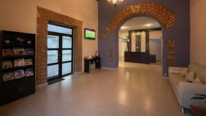 A spacious lobby with a reception desk, a fireplace, and a television. - Hotel Santa Julia  (Tecamachalco)