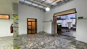 A spacious indoor area with a tiled floor, a fire extinguisher, and a door leading outside. - Hotel Santa Julia  (Tecamachalco)