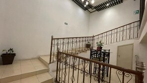 A staircase with ornate metal railings, a potted plant, and a table with chairs. - Hotel Santa Julia  (Tecamachalco)