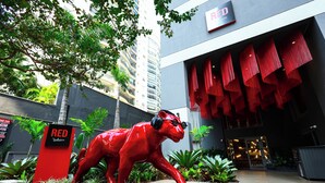 A red statue of a bull in front of a building with a sign that reads 'RED.' - Radisson RED Ibirapuera (Sao Paulo)