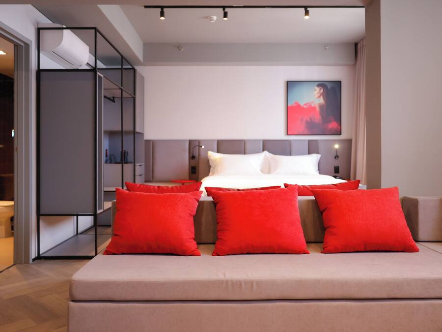 Un dormitorio moderno con una cama, almohadas rojas y un cuadro en la pared.