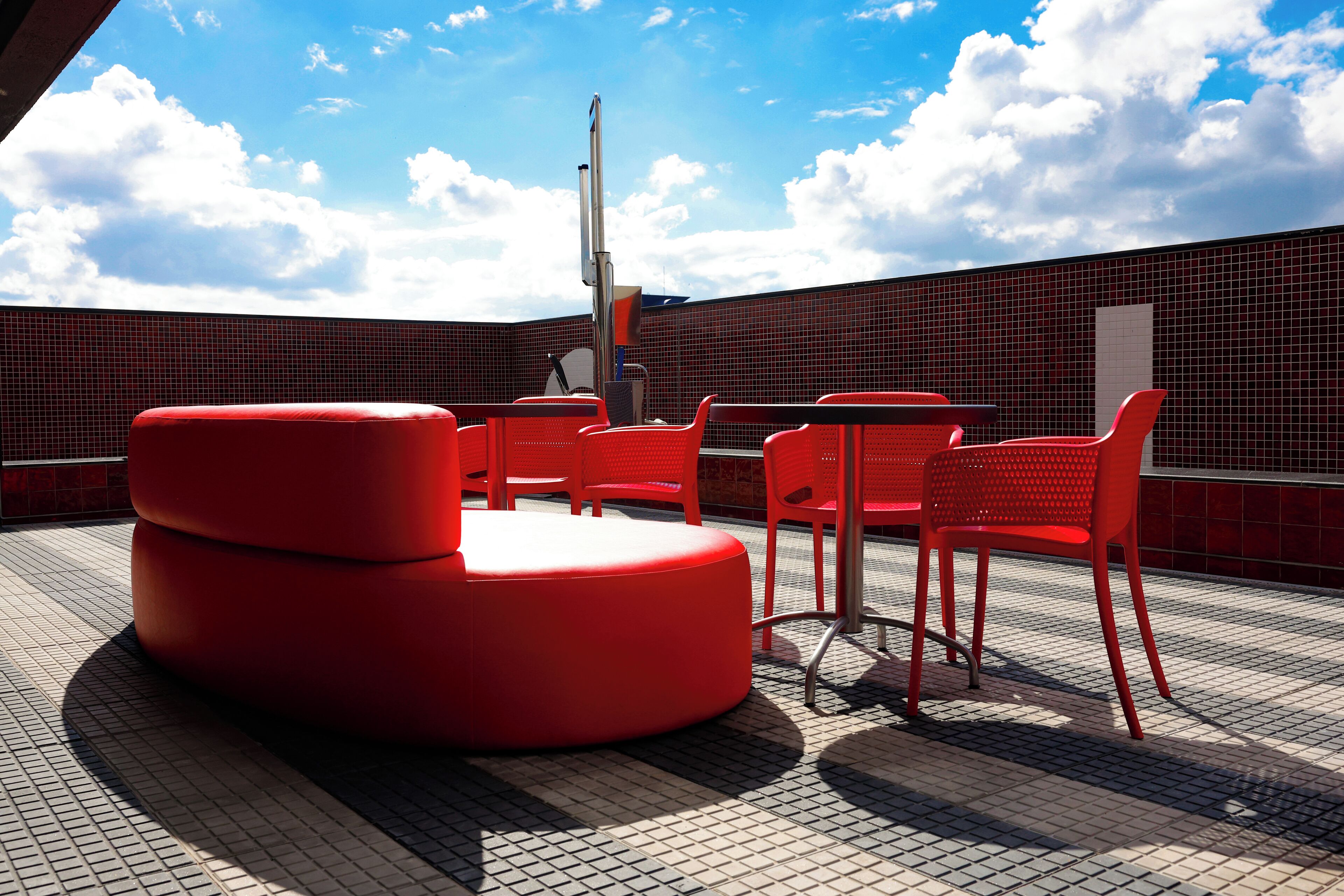 A rooftop terrace with red seating and a tiled floor.