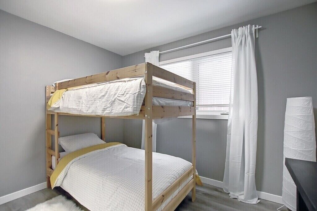 A bunk bed room with a window and curtains.