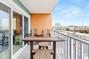 Ein Balkon mit Tisch und Stühlen, Blick auf die Stadt und ein Gebäude im Hintergrund.