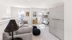 Amplia sala de estar con un conjunto de sofás, una lámpara, una escalera y un mueble de almacenaje.