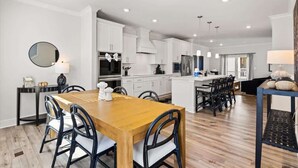 Una cocina moderna con armarios blancos, una mesa de comedor de madera y sillas negras.