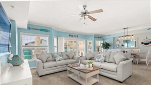 A living room with a sectional sofa, a coffee table, and a ceiling fan. - Seaside Escape Mansion (Ocean City)