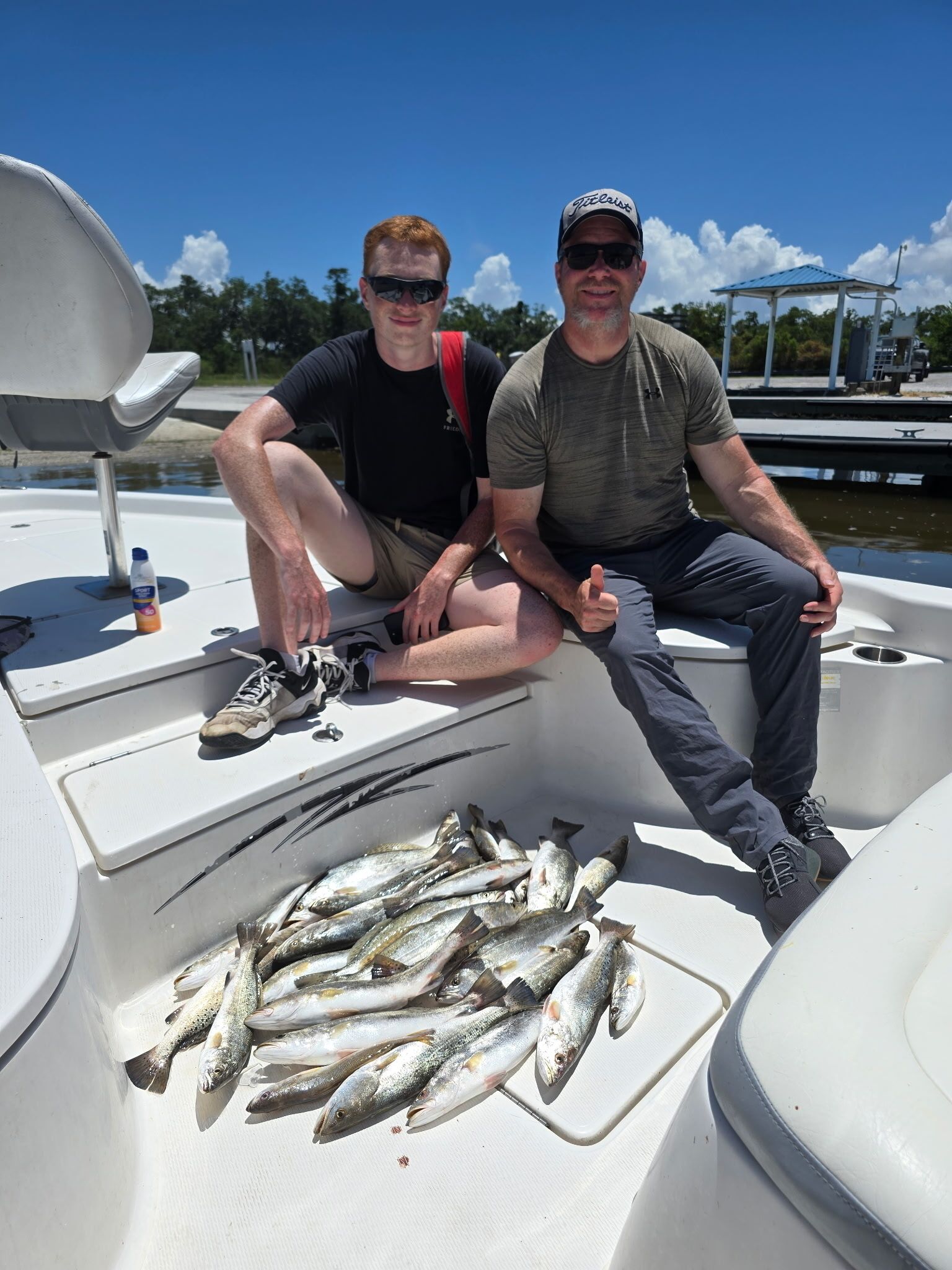 Deux personnes sont assises dans un bateau, devant lesquelles se trouve un tas de poissons.