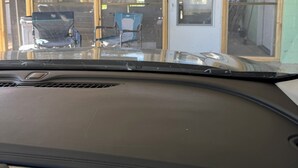 Blick durch eine Autoscheibe auf ein Gebäude mit Holzboden und großen Glasüren.