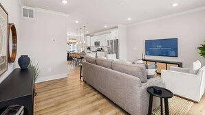 A modern living room with a sofa, a coffee table, and a TV mounted on the wall.