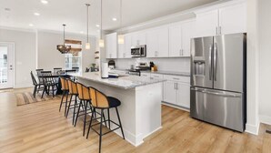 A modern kitchen with white cabinets, stainless steel appliances, and a central island with bar stools.