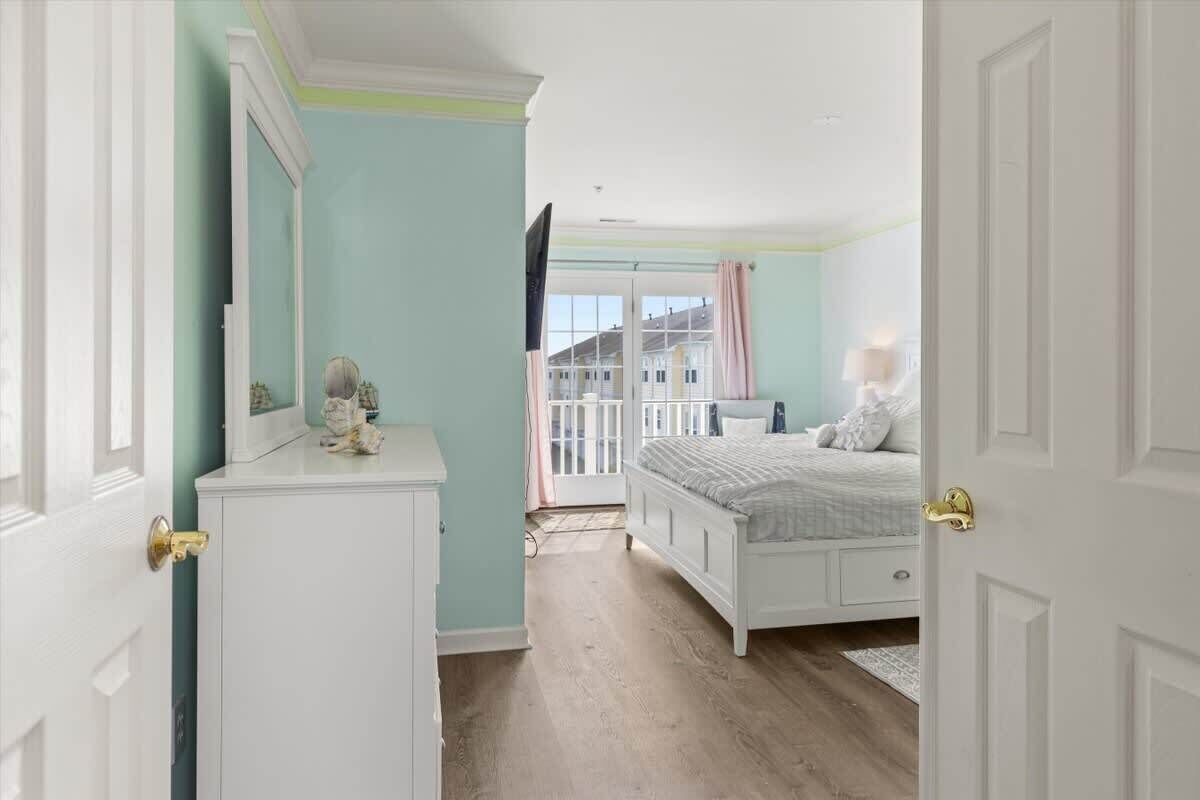 A bedroom with a bed, dresser, and a window with curtains.