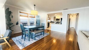 A spacious living area with a dining table, chairs, and a kitchen in the background.