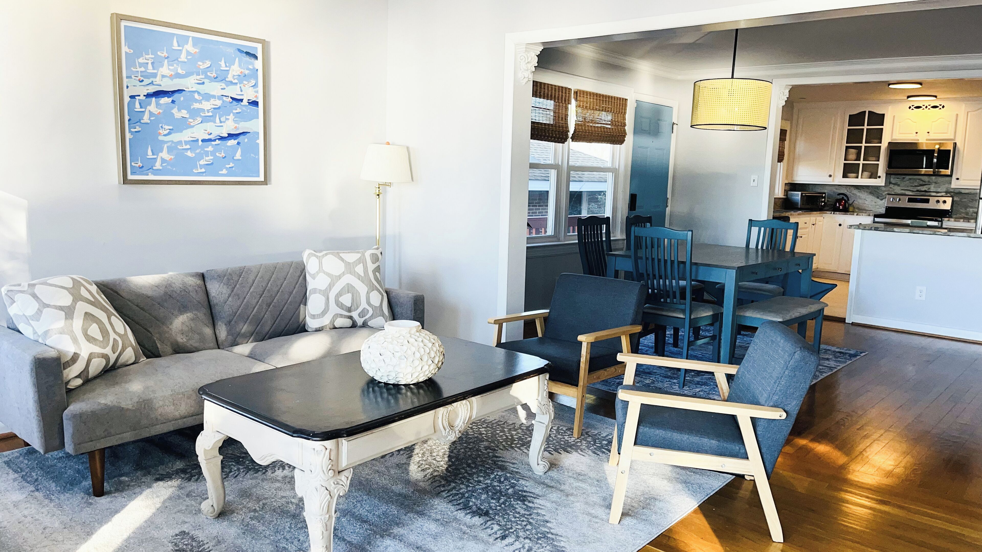 Un salon moderne comprenant un canapé, une table basse et des fauteuils, un coin repas avec une table et des chaises, et une cuisine équipée d’un four à micro-ondes et d’une cuisinière.