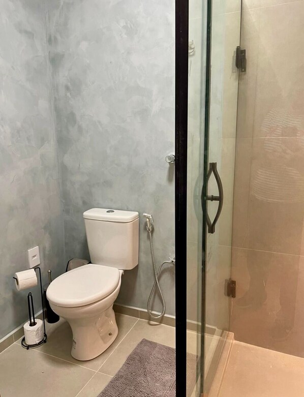 A bathroom with a toilet, a glass shower enclosure, and a towel rack.