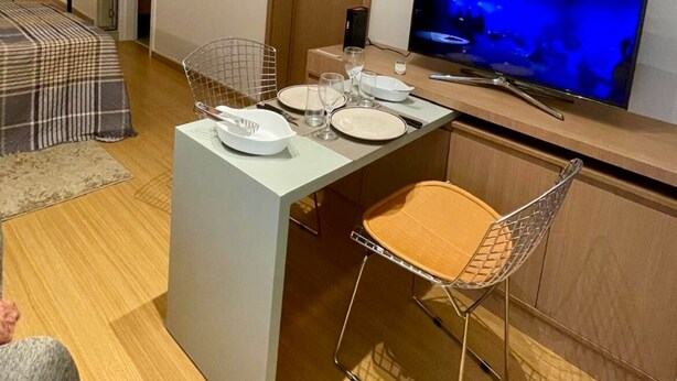 Un espacio habitable compacto con kitchenette, comedor con televisor y cama.