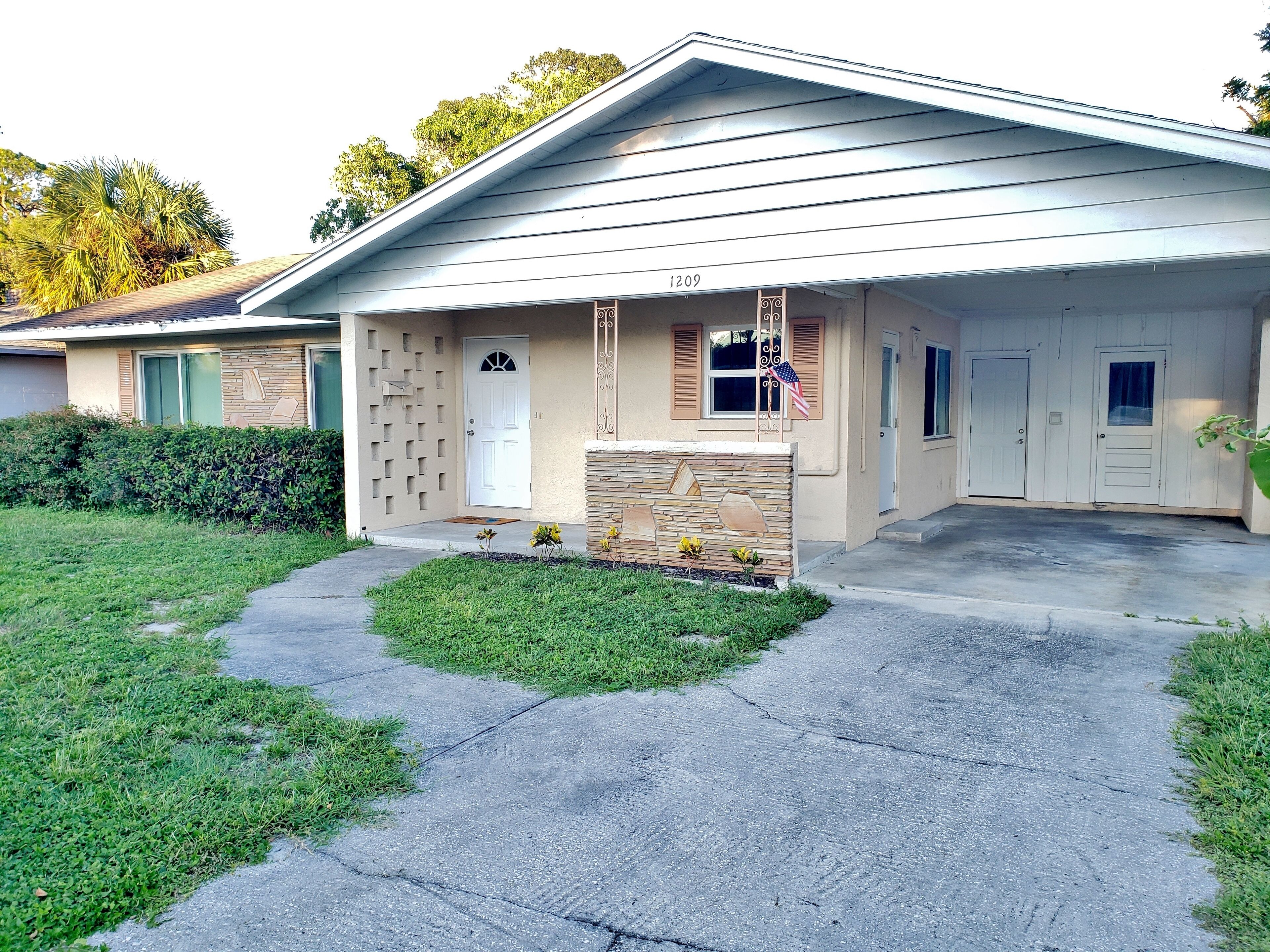 A single-story house with a front porch, a mailbox, and a small garden.