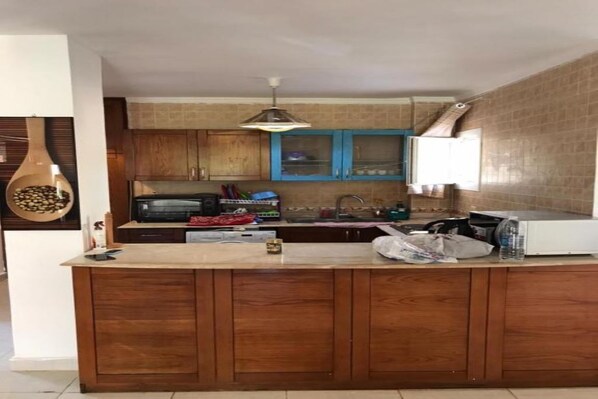 A kitchen with wooden cabinets, a central island, a microwave, and a hanging light fixture.
