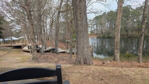Une terrasse en bois avec un banc, donnant sur un lac entouré d’arbres.