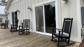 Een houten terras met schommelstoelen en een schuifdeur naar een overdekt terras.